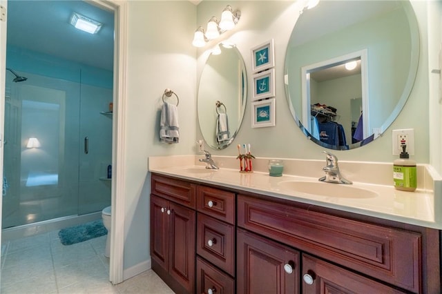 bathroom featuring a sink, a stall shower, toilet, and double vanity