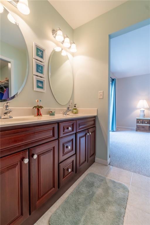 bathroom with double vanity, baseboards, tile patterned flooring, and a sink
