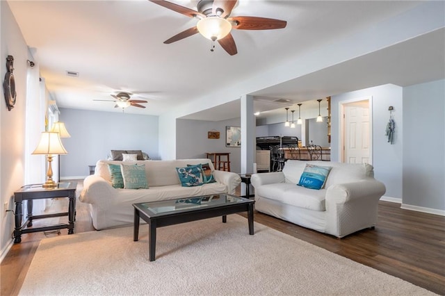 living area featuring a ceiling fan, baseboards, visible vents, and wood finished floors