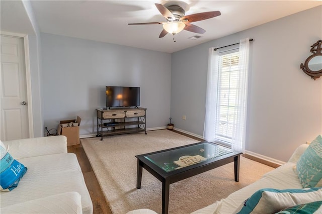 living area featuring baseboards and a ceiling fan
