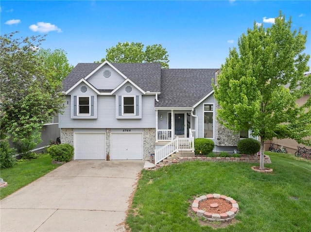 tri-level home with a garage, stone siding, a front yard, roof with shingles, and driveway