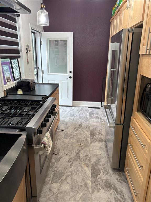 1316 Santa Fe St, Atchison, KS 66002 - kitchen with premium appliances, light brown cabinetry, decorative light fixtures, and baseboards