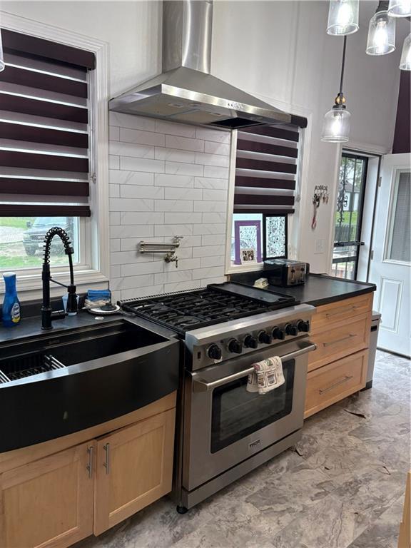 1316 Santa Fe St, Atchison, KS 66002 - kitchen with stainless steel range, wall chimney range hood, plenty of natural light, and a sink