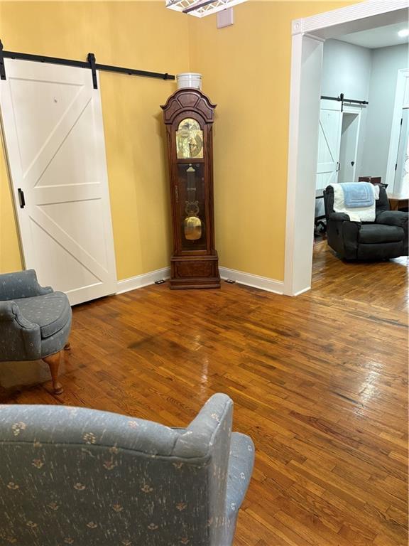 1316 Santa Fe St, Atchison, KS 66002 - living room featuring a barn door, baseboards, and hardwood / wood-style flooring
