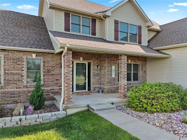 view of front of home with a porch, brick siding, and roof with shingles