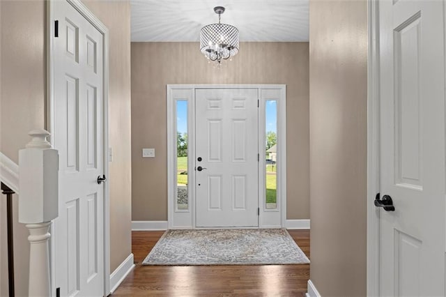 entrance foyer featuring baseboards, dark wood finished floors, and a notable chandelier