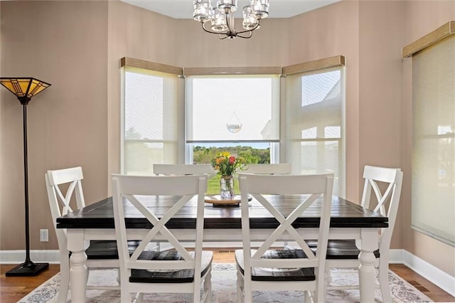 dining area featuring baseboards, wood finished floors, and a chandelier