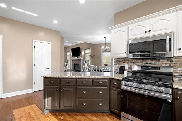kitchen featuring appliances with stainless steel finishes, white cabinets, dark brown cabinetry, and a peninsula