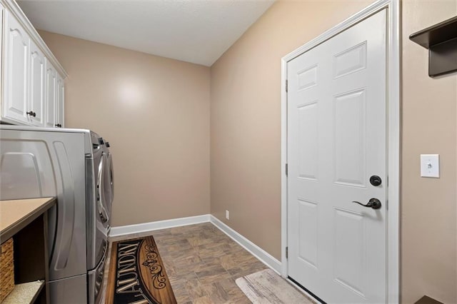 laundry room with cabinet space, baseboards, washing machine and dryer, and stone finish floor