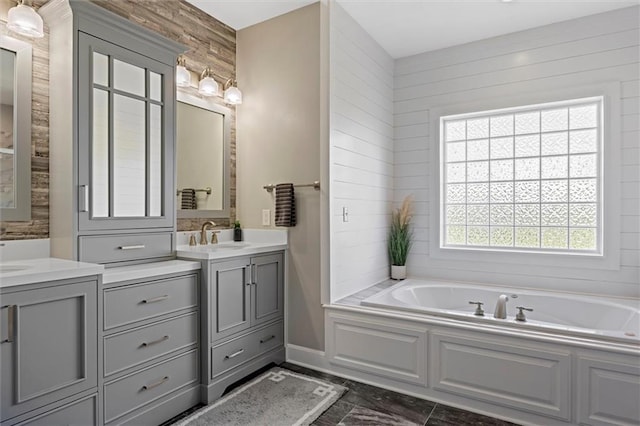 bathroom with a garden tub, a sink, two vanities, and a healthy amount of sunlight