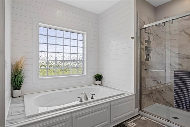 bathroom featuring a marble finish shower and a garden tub