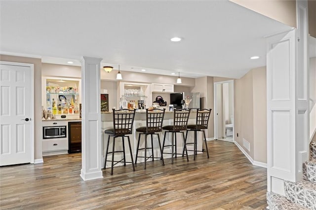 kitchen with appliances with stainless steel finishes, a kitchen breakfast bar, light wood-style flooring, and visible vents
