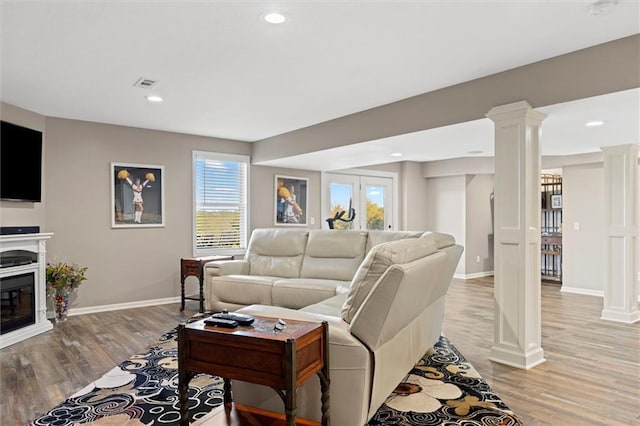 living room featuring visible vents, plenty of natural light, ornate columns, and light wood-type flooring
