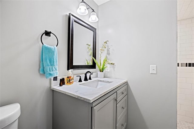 full bath featuring toilet, a tile shower, and vanity