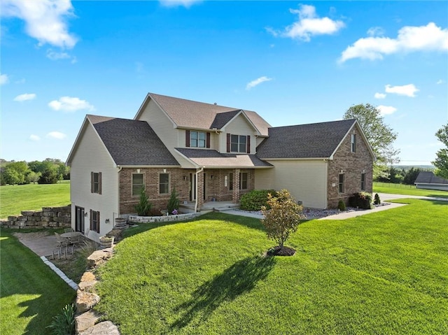 traditional home with brick siding, a shingled roof, and a front lawn