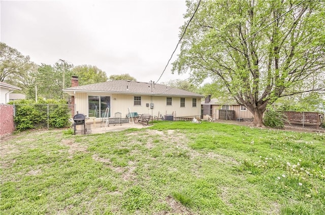 back of property with a chimney, a fenced backyard, a lawn, and a patio area