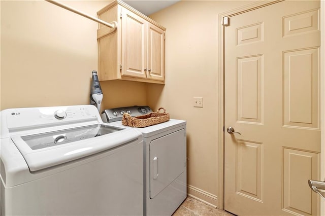 washroom featuring baseboards, independent washer and dryer, and cabinet space