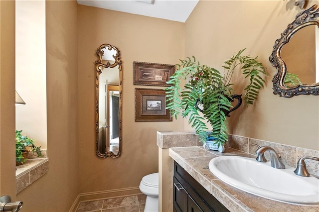 bathroom with toilet, baseboards, vanity, and tile patterned flooring