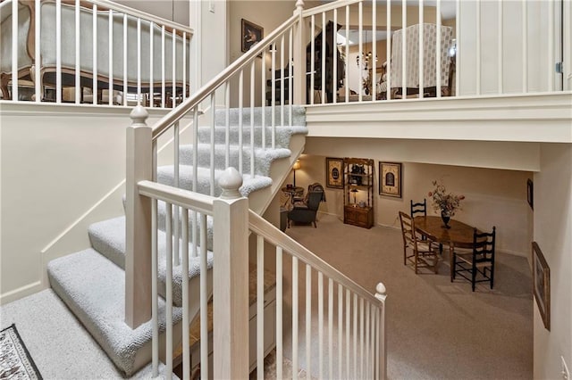 staircase with carpet and a towering ceiling