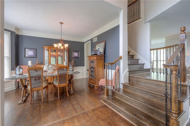 dining room featuring crown molding, a notable chandelier, a textured ceiling, stairs, and wood finished floors