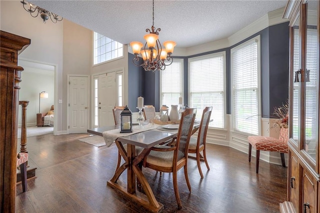 dining area featuring ornamental molding, a textured ceiling, dark wood-style flooring, and a notable chandelier