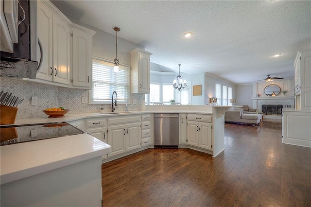 kitchen featuring plenty of natural light, appliances with stainless steel finishes, dark wood finished floors, a sink, and a peninsula