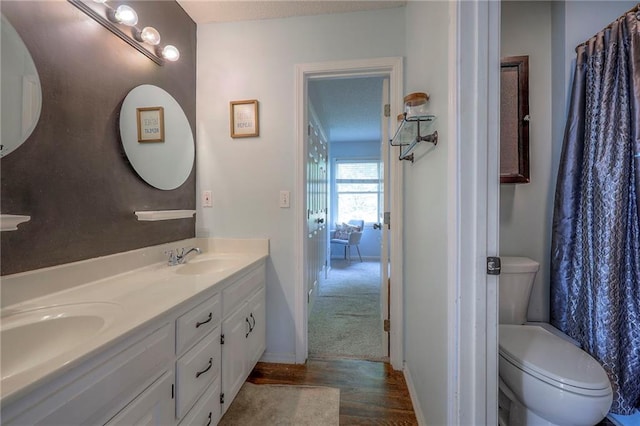 bathroom with double vanity, a sink, wood finished floors, and toilet