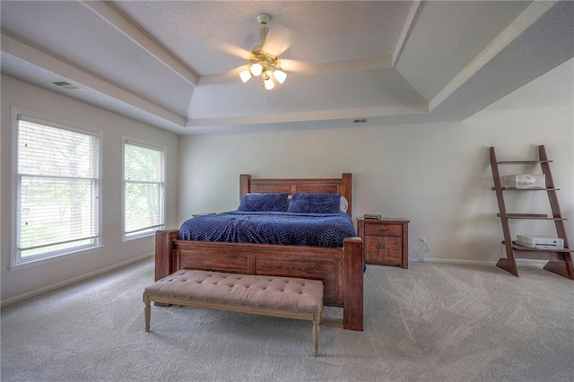 carpeted bedroom with baseboards, visible vents, ceiling fan, and a raised ceiling