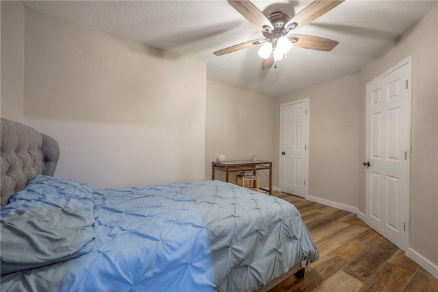 bedroom with baseboards, a textured ceiling, ceiling fan, and wood finished floors