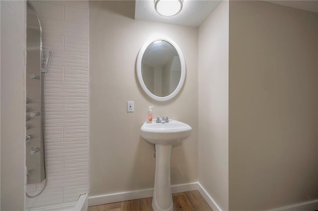 bathroom with wood finished floors, a textured ceiling, baseboards, and a shower