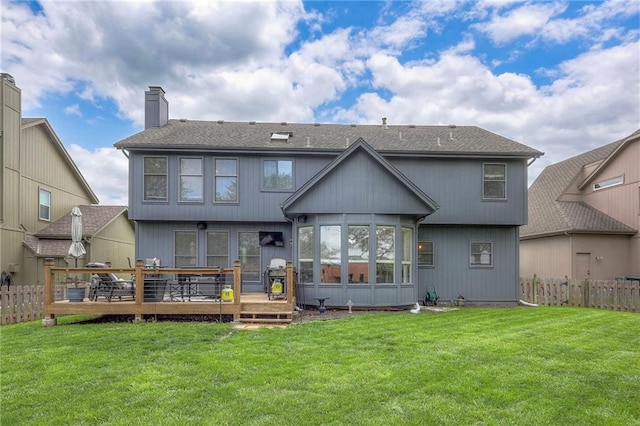 rear view of property featuring a lawn, a wooden deck, a chimney, and fence