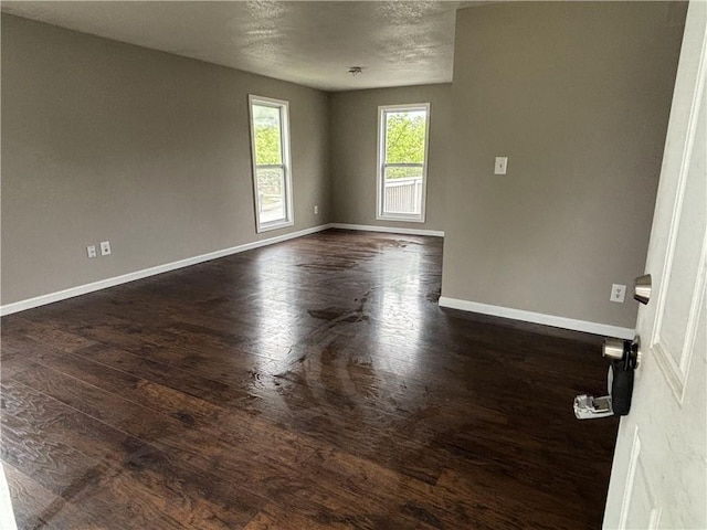 empty room with dark wood finished floors and baseboards