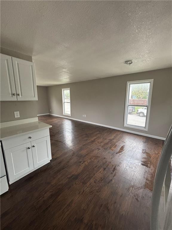 interior space featuring dark wood-style floors, a textured ceiling, and baseboards