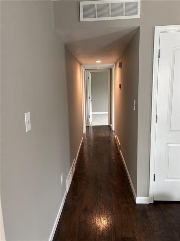corridor featuring dark wood finished floors, visible vents, and baseboards