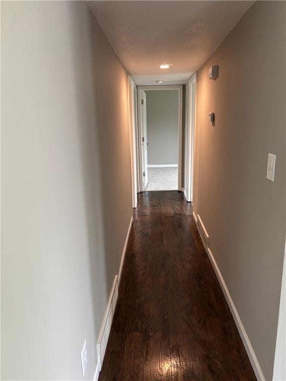 corridor featuring dark wood-style floors, visible vents, and baseboards