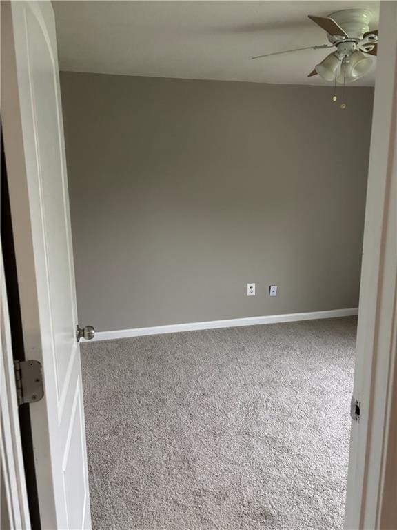 carpeted spare room with a ceiling fan and baseboards