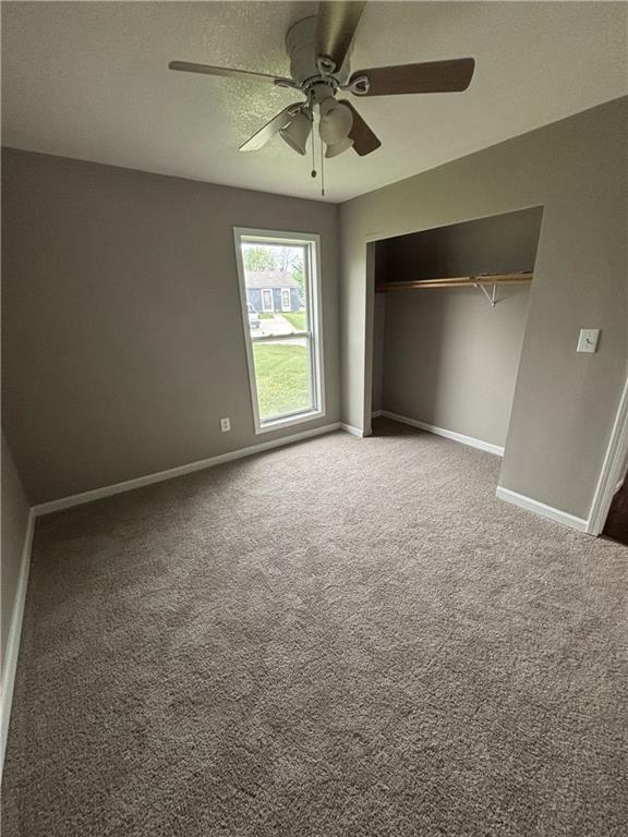 unfurnished bedroom with baseboards, a ceiling fan, carpet, and a closet
