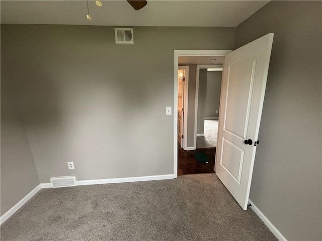 spare room featuring baseboards, visible vents, and dark carpet