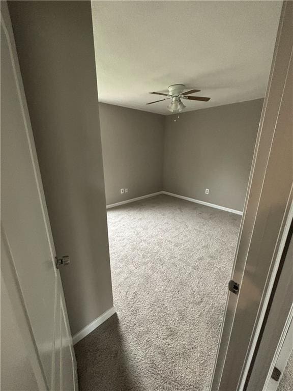 carpeted empty room featuring ceiling fan and baseboards