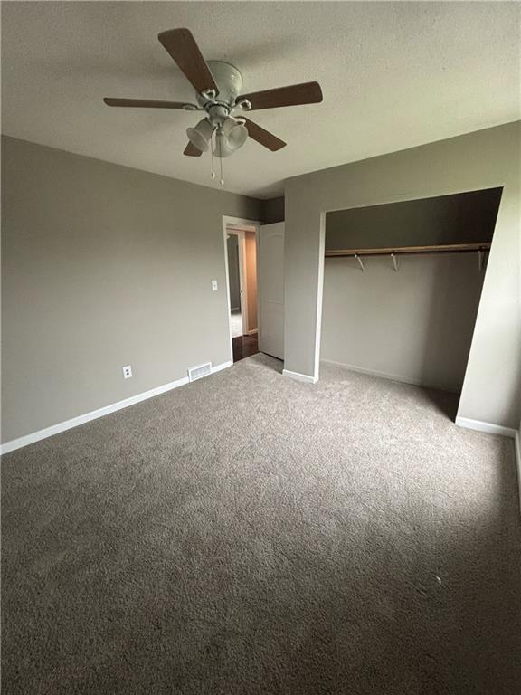 unfurnished bedroom featuring a closet, ceiling fan, visible vents, carpet, and baseboards