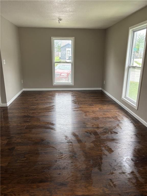 unfurnished room with baseboards and dark wood-style flooring