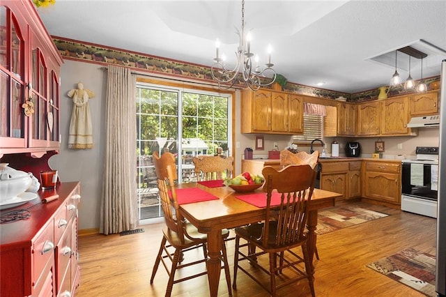 dining space featuring light wood finished floors, a chandelier, and baseboards