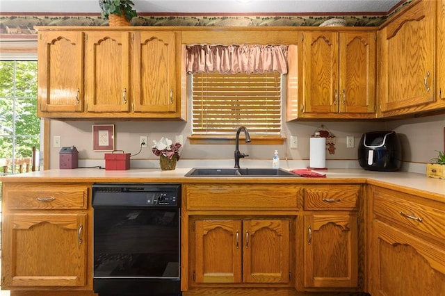 kitchen with black dishwasher, a sink, light countertops, and brown cabinetry