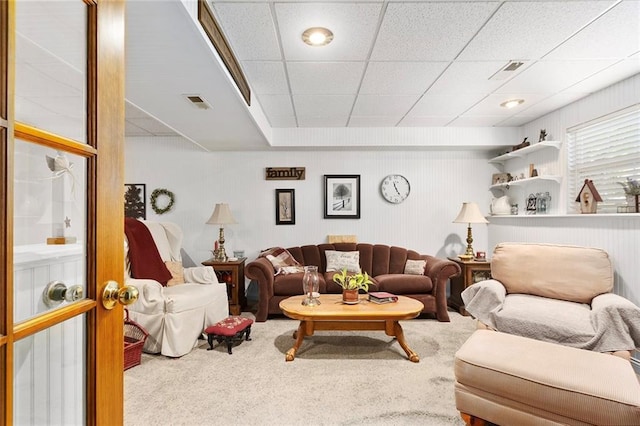 carpeted living area with a paneled ceiling