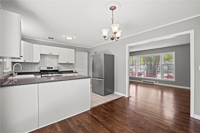 kitchen with appliances with stainless steel finishes, a sink, dark countertops, and wood finished floors