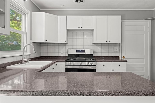 kitchen featuring stainless steel gas stove, a sink, white cabinetry, and decorative backsplash