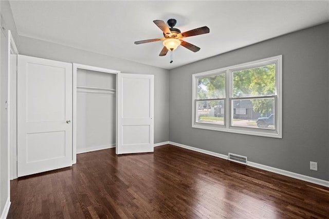 unfurnished bedroom with dark wood-type flooring, baseboards, a closet, and a ceiling fan