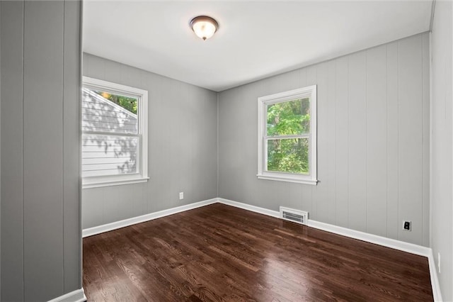 spare room featuring dark wood-style floors, plenty of natural light, and baseboards