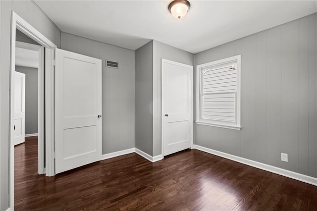 unfurnished bedroom with dark wood-style floors, baseboards, and a closet