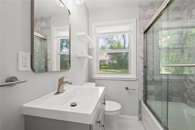 bathroom featuring vanity, toilet, tile patterned flooring, combined bath / shower with glass door, and baseboards